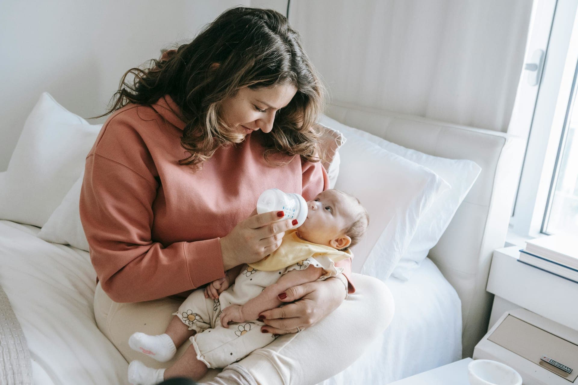 Caregiver bottle feeding a baby in warm light